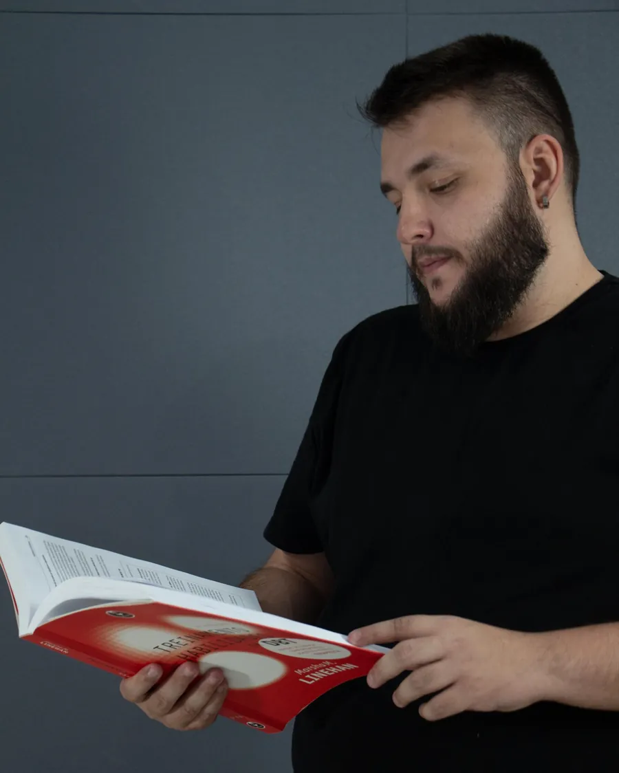 Vitor Augusto lendo um manual de treinamento de habilidades em DBT
